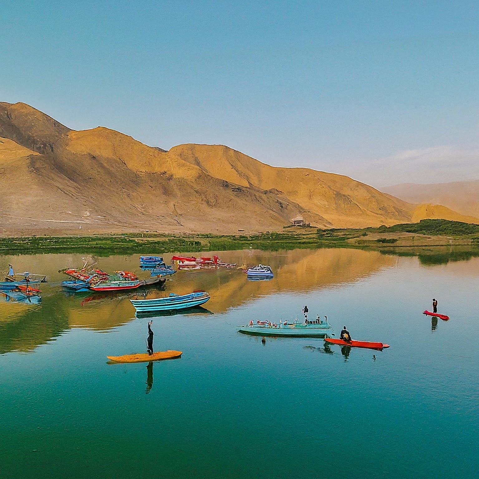 Lar Lake, Iran, with colorful boats, people kayaking and enjoying water activities.