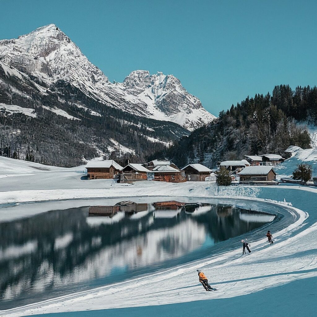 Winter wonderland in Steg, Liechtenstein, with snow-covered chalets, frozen lake, and skiers.